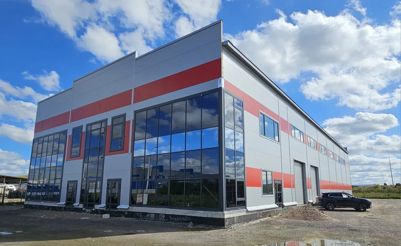 Магазин-склад с АБК 1 500 м² в Шушарах: витражный фасад административной части и складской корпус с красными поясами