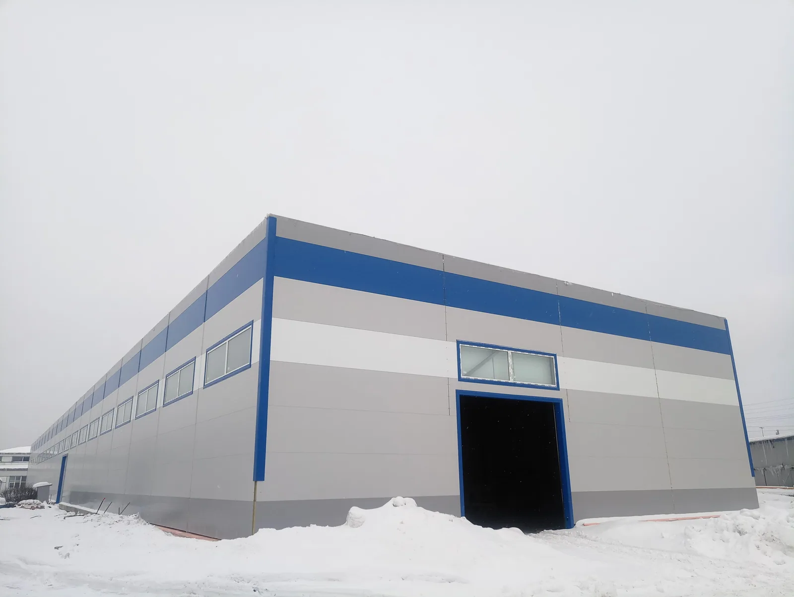 Здание на Софийской 05.02.2019: стены закрыты, ряд окон по длинной стене, в торце — проём под ворота, снег
